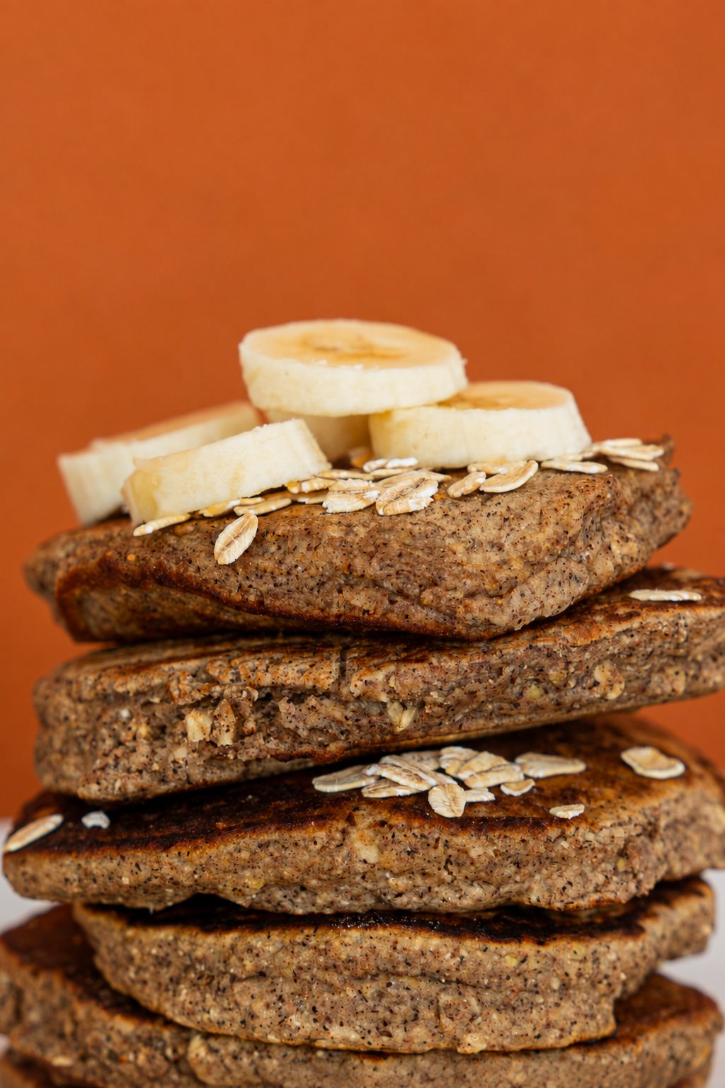 A close-up stack of Sol Food cinnamon oat pancakes topped with banana and oats