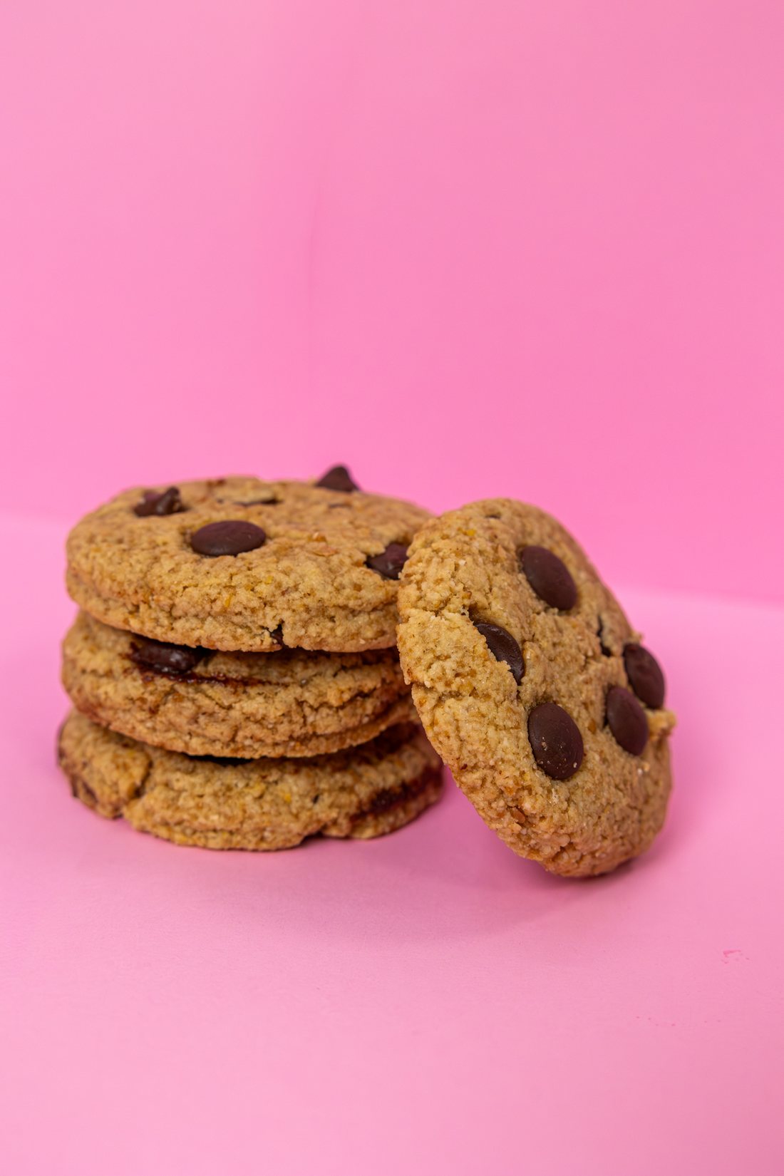 A stack of Sol Food chocolate chip cookies on a pink background